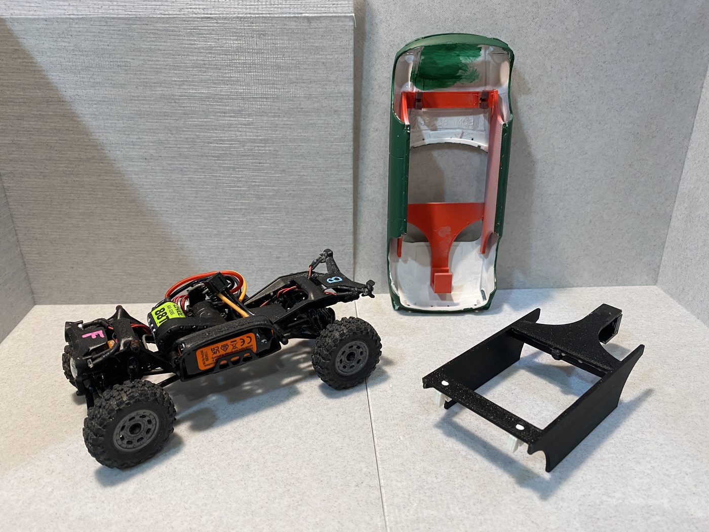 A chassis, a body turned upside down with parts glued inside, and a cut-down shell laid out side by side.